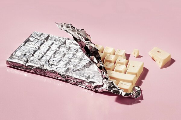 White keyboard in the form of chocolate in a torn wrapper