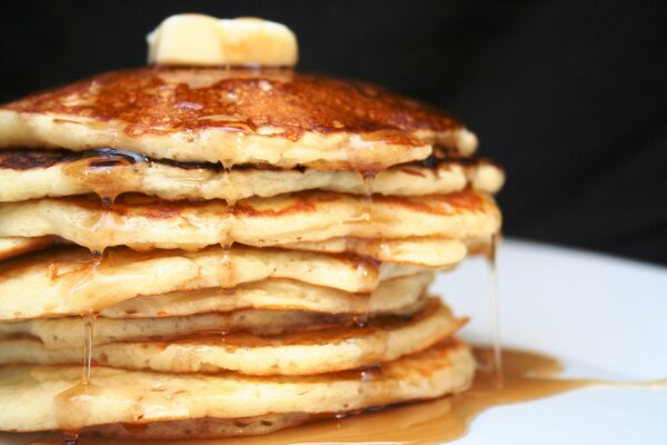 Arrêt de pancakes arrosés de miel sur une plaque blanche