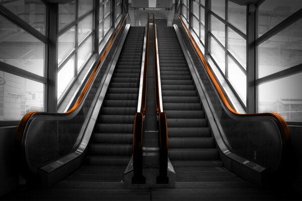 Graue Rolltreppe mit orangefarbenem Geländer