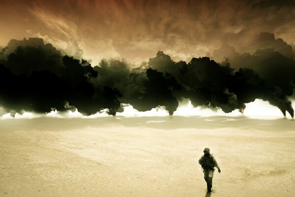 A man walks on the sand against a background of black smoke