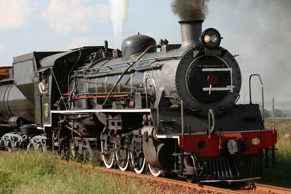 A black steam locomotive is rolling along the rails