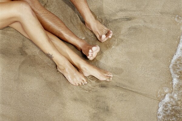 Men s and women s legs on the beach