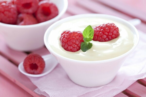 Postre de leche con frambuesas en una taza blanca