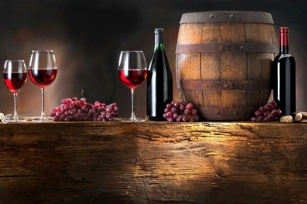 Wine in glasses and grapes on the table with a barrel