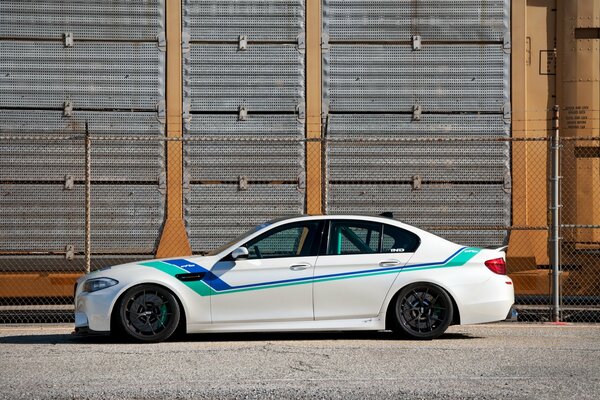 BMW M5 bianco con strisce colorate, vista laterale