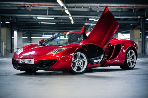 The red McLaren is standing sideways in the parking lot