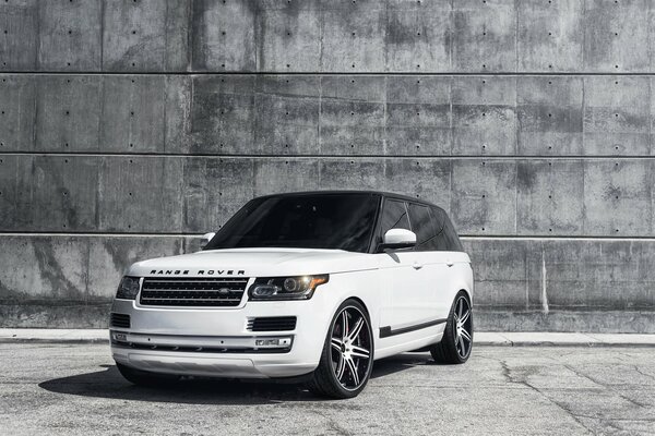 Land rover blanco con cristales oscuros en la pared gris