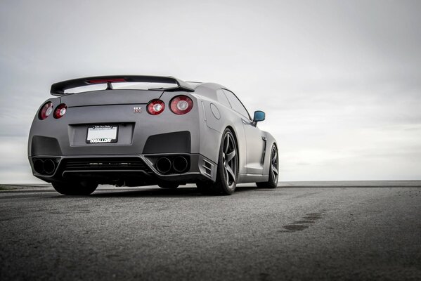 A black Nissan at the horizon of a bright sky 