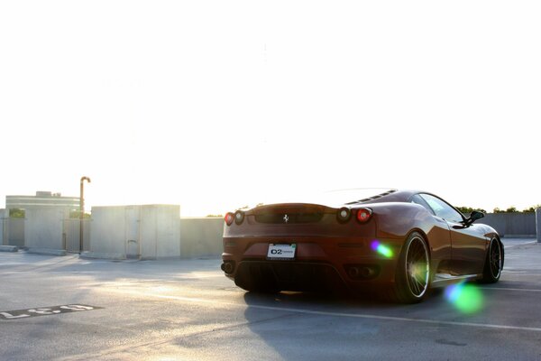 Dark red Ferrari in the sunlight. Glare