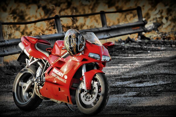 Motocicleta deportiva roja con casco que pesa en la tira de la manija