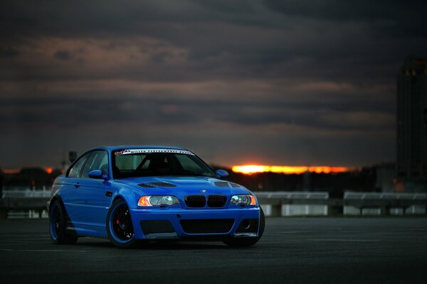 BMW azul y nubes de puesta de sol en la parte trasera