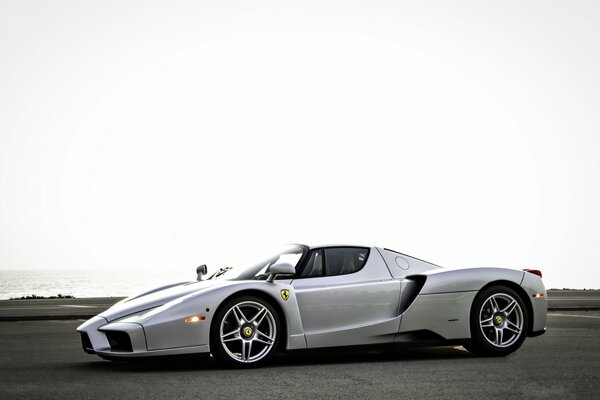 Ein silberner Ferrari steht auf dem Parkplatz. Das Meer im Hintergrund