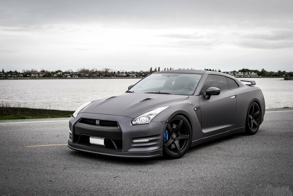 Matte black nissan on a gray sky background