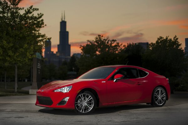 A red car is driving down a Chicago street