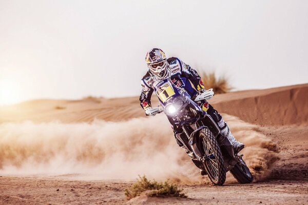 A motorcyclist during a race with flying sand