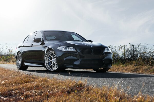 Front view of a black BMW m5 amid a beautiful sky