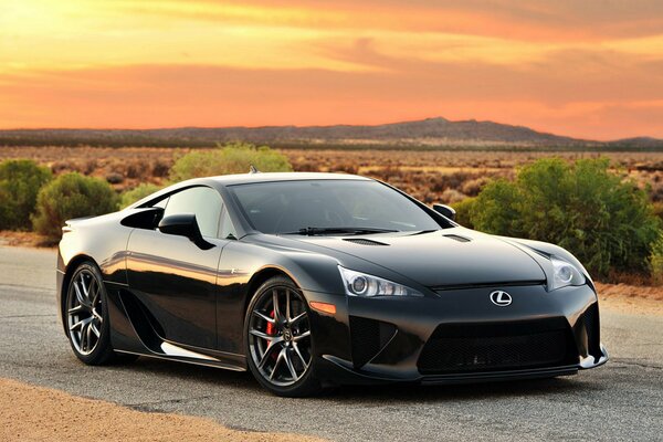 Black lexus on the prairie road at sunset