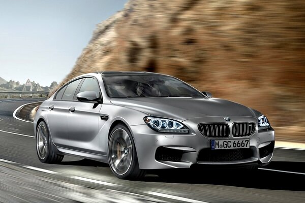 BMW M6 Gran coupe jeździ z dużą prędkością po pagórkowatym terenie