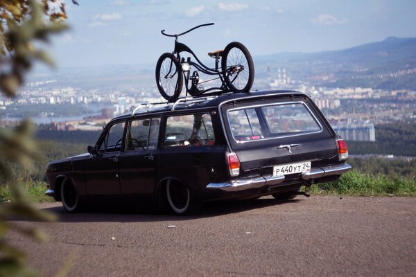 Volga rara con una bicicleta en el techo en el fondo de la ciudad