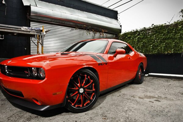 A red challenger sports car is parked at the garage