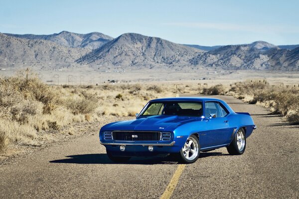 Blue chevrolet on the road against the background of mountains