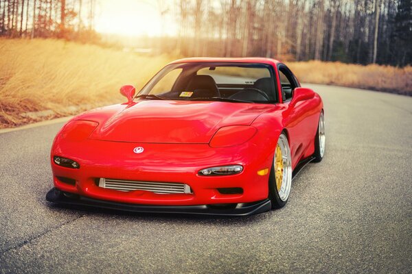 Tuning rouge Mazda RX-7 sur la piste dans les rayons du soleil