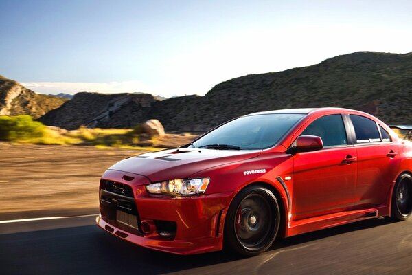 A red Mitsubishi Lancer car rushes along the American highway