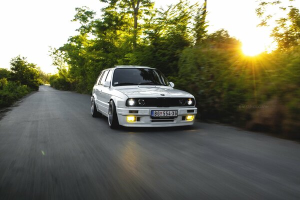 Coche bmw E30 blanco en el fondo de la puesta de sol