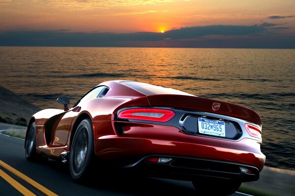 Rouge puissant Dodge Viper chevauche la route sur fond de mer