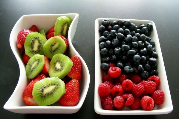 Sliced fruits and berries in white bowls