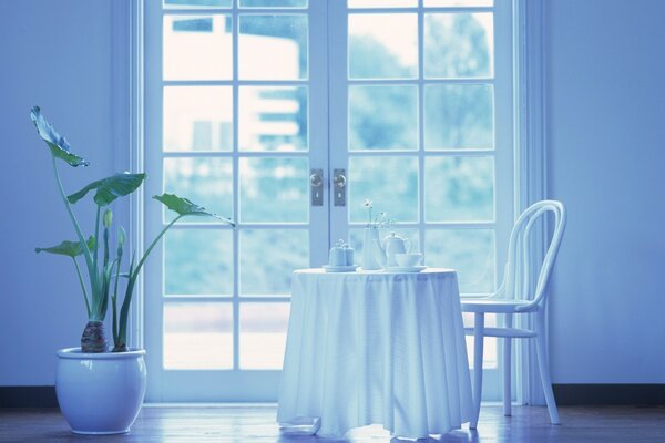 A table with tea utensils and a tub with a plant next to it