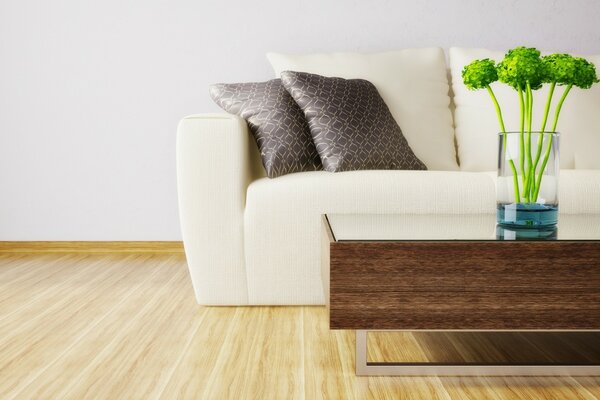 Gray pillows on a white sofa and a vase on the table