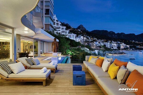 Terraza con tumbonas y vistas al océano y la ciudad de la noche