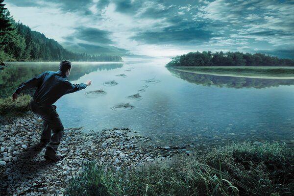 A man throws stones into the river near the forest