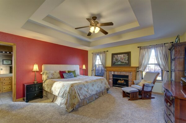 Bedroom with double bed, armchair and fireplace in pink and beige tones