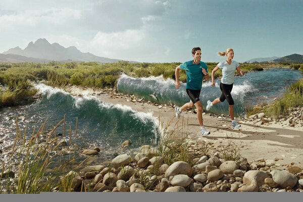 Two happy people are running along a dirt track