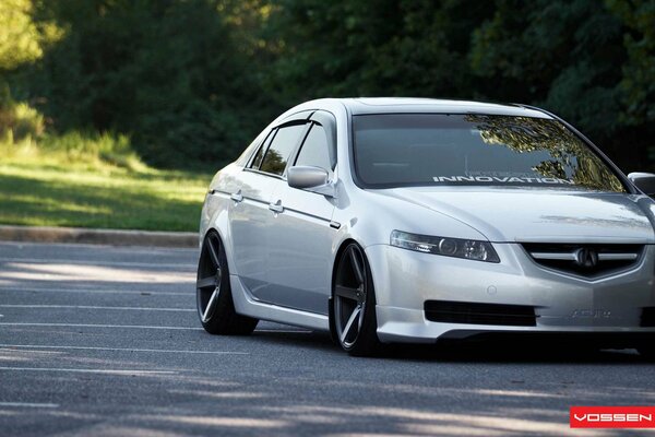 Un automóvil acura TL de color blanco se encuentra cerca de los árboles