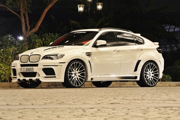 Bianco bmw di notte sulla strada in illuminazione Fanari