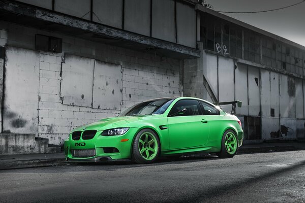 Una BMW verde si trova vicino a un edificio abbandonato