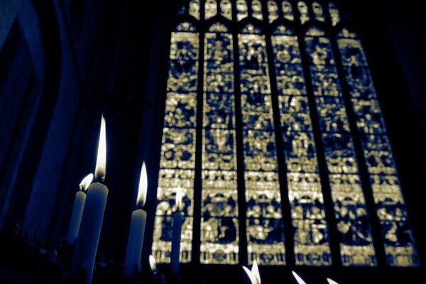 Immagine scura di candele in chiesa, grandi vetrate