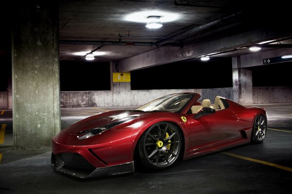 Czerwony Ferrari spider na nocnym wielopoziomowym parkingu