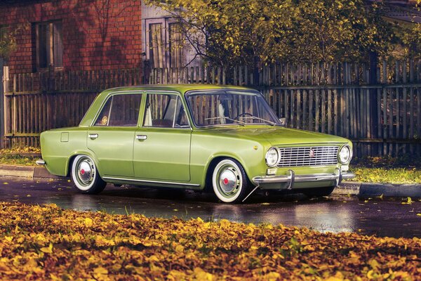 Lada s car is standing in the leaves at the gate in autumn