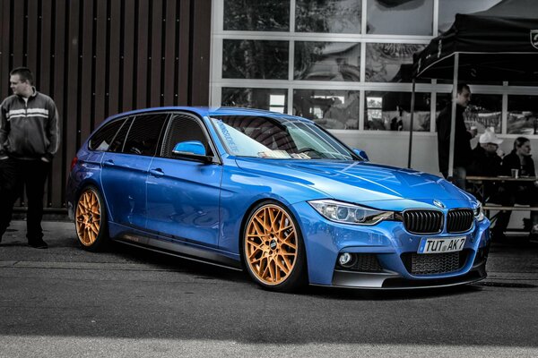 Blue BMW with yellow wheels on a black and white background