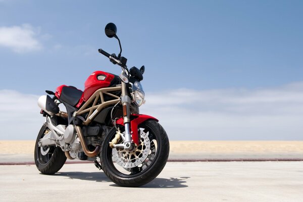 Sur la plage sur fond de ciel - moto de sport rouge