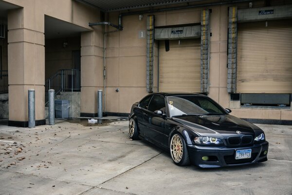 A black BMW is parked outside a closed store