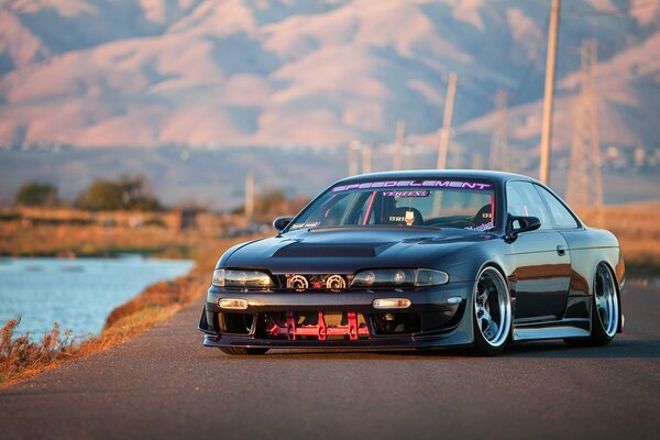 Nissan 240SX sintonizado en el fondo de las montañas y el cuerpo de agua