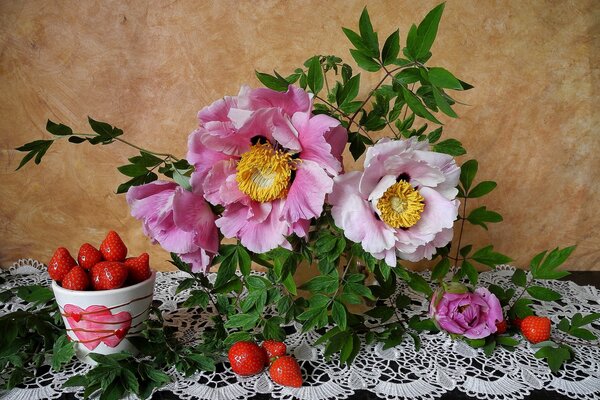 Erdbeeren und Blumen auf dem Tisch mit Tischdecke