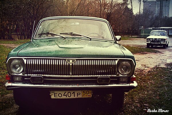 A green Volga car and a white Moskvich car