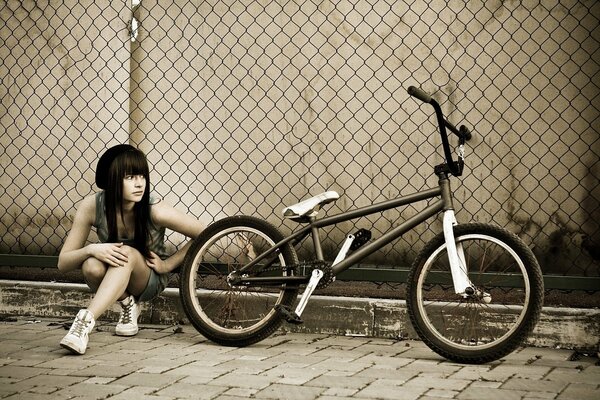 Fille avec un vélo bmx le long de la clôture dans le filet