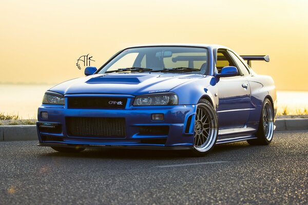 A blue car on the road against the background of sunset